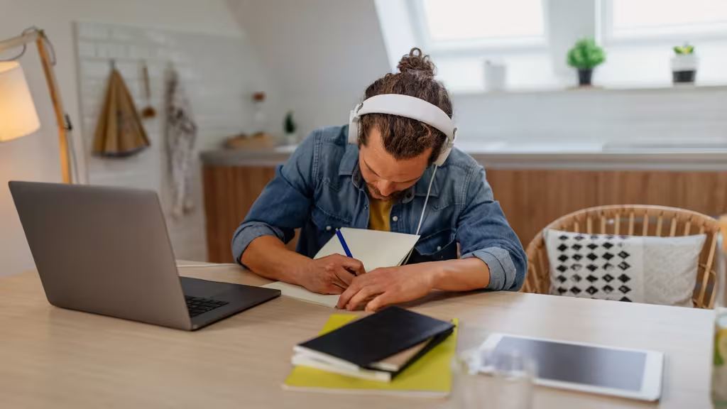 How To Practice Self-Leadership For Business Success 6 man wearing headphones writing something down in his notebook