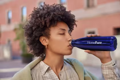 A woman drinks from her HomePure reusable bottle, advocating health, cleanliness, and sustainability through hydration.