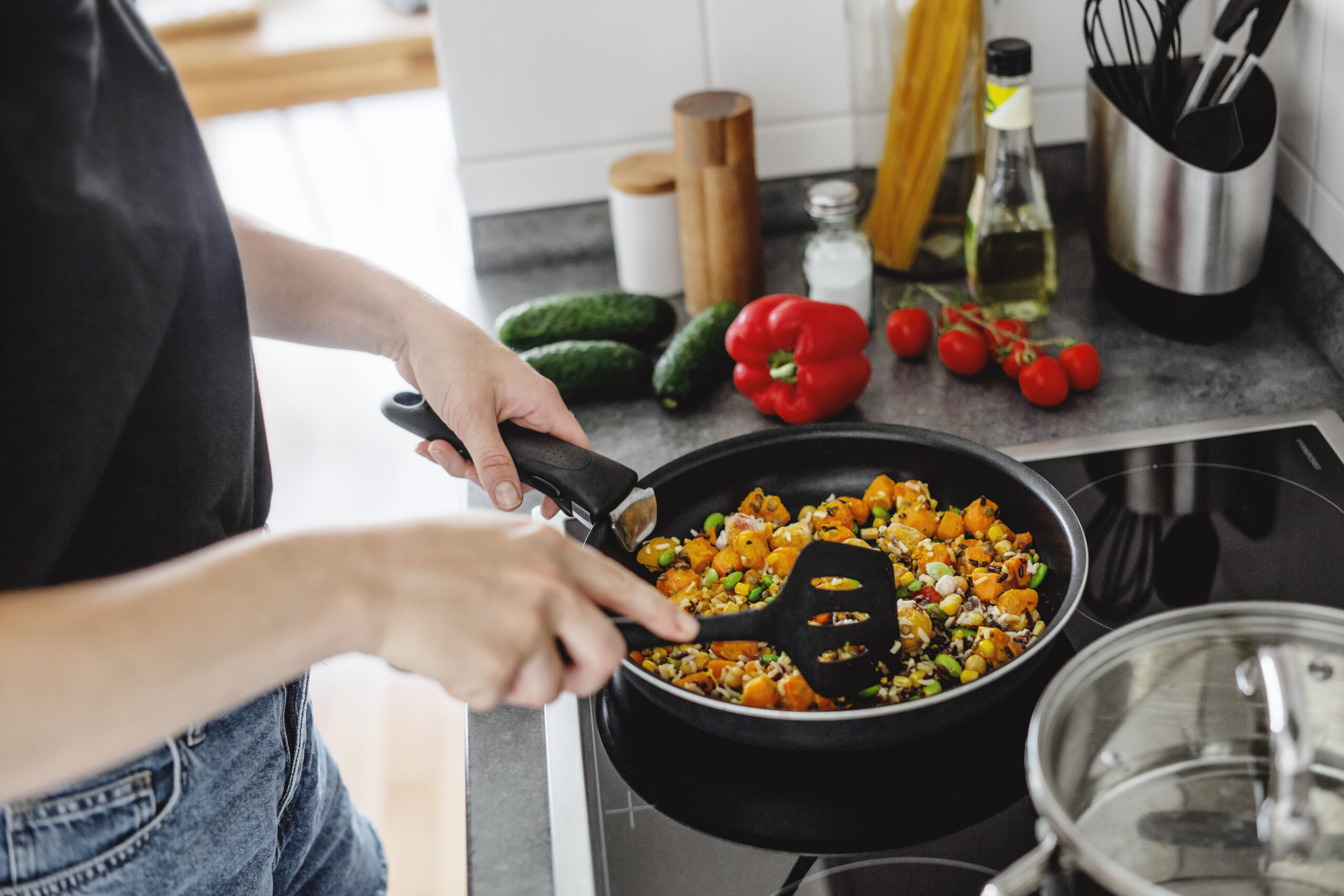 Woman preparing a meal with leftover vegetables and ingredients to reduce food waste.