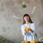 Woman who enjoys a plant-based diet juggling EDG3 Plus packets with broccoli and bell pepper