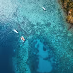 A stunning aerial perspective of a serene lagoon, featuring small fishing boats gracefully adrift on its tranquil surface.
