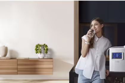 Woman standing next to homepure viva drinking water in kitchen