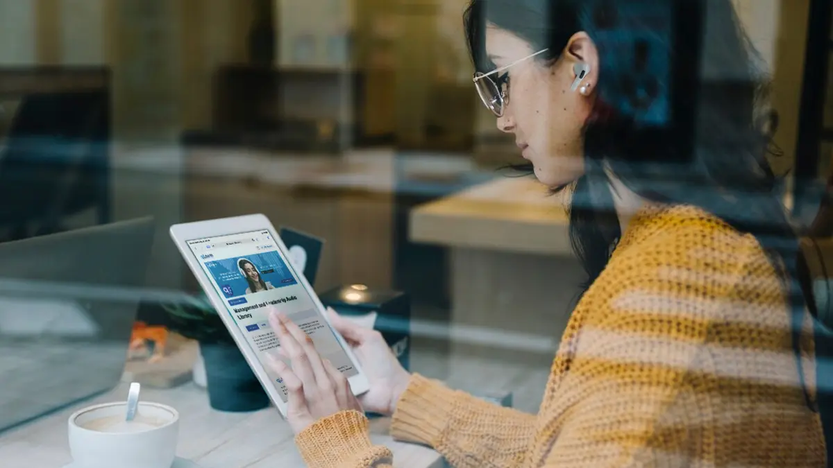 Gift Guide For Him: Gift Ideas For The Men In Your Life This Father'S Day 5 Caucasian girl engaging in hybrid learning with qLearn's management and leadership audio library on her tablet while she's at a cafe