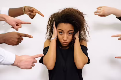 girl with hands over ears wondering how do you handle criticism symbolised by other people's hands pointing at her