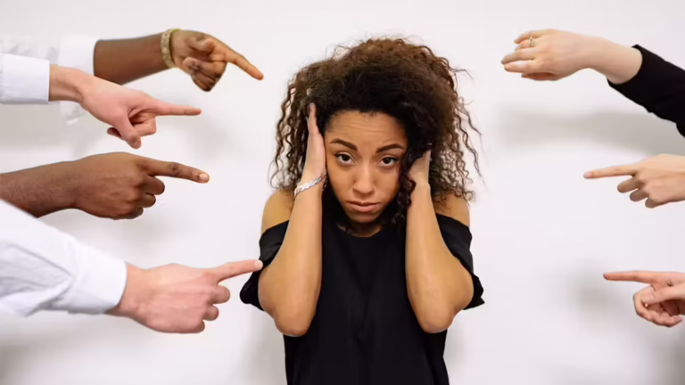 girl with hands over ears wondering how do you handle criticism symbolised by other people's hands pointing at her